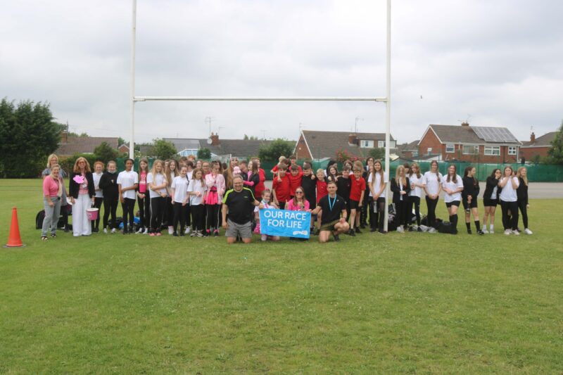 students in the school yard celebrating the money they raised for race for life