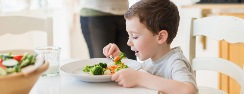 a child eating vegetables at a dinner table