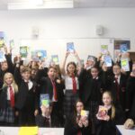 students in a classroom at South Wirral High school holding up books from bookbuzz