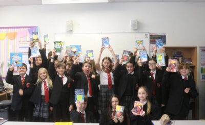 students in a classroom at South Wirral High school holding up books from bookbuzz