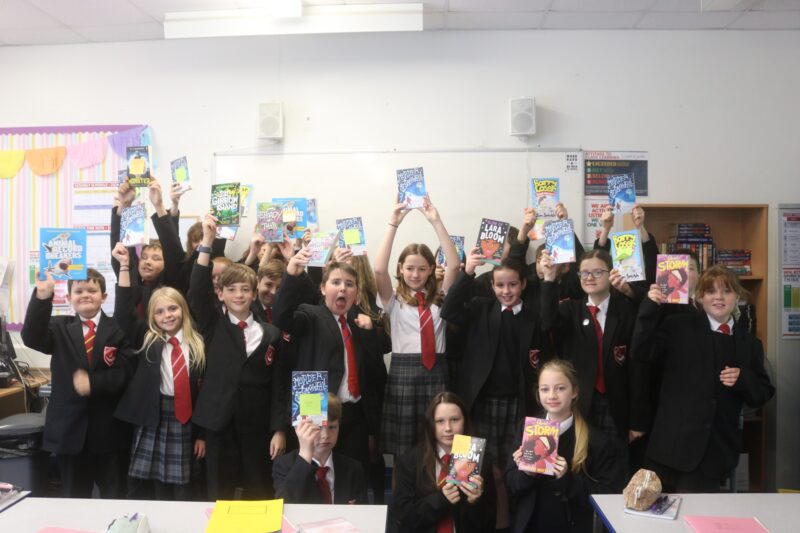 students in a classroom at South Wirral High school holding up books from bookbuzz